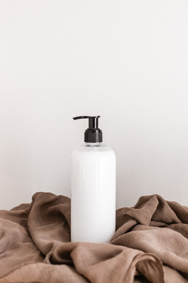 white Silk moisturizer in a clear bottle on a cloth with a white background