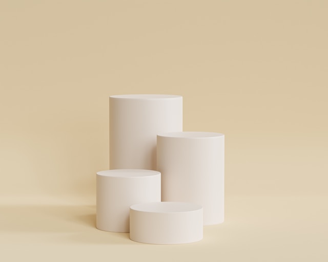 4 white cylinder cans of makeup in front of a beige background