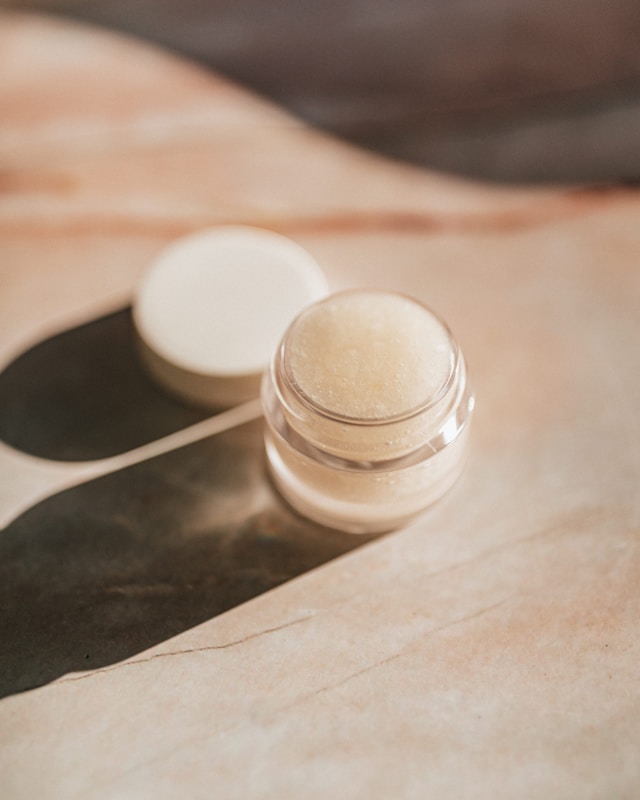an opened jar of powder makeup on a tan table